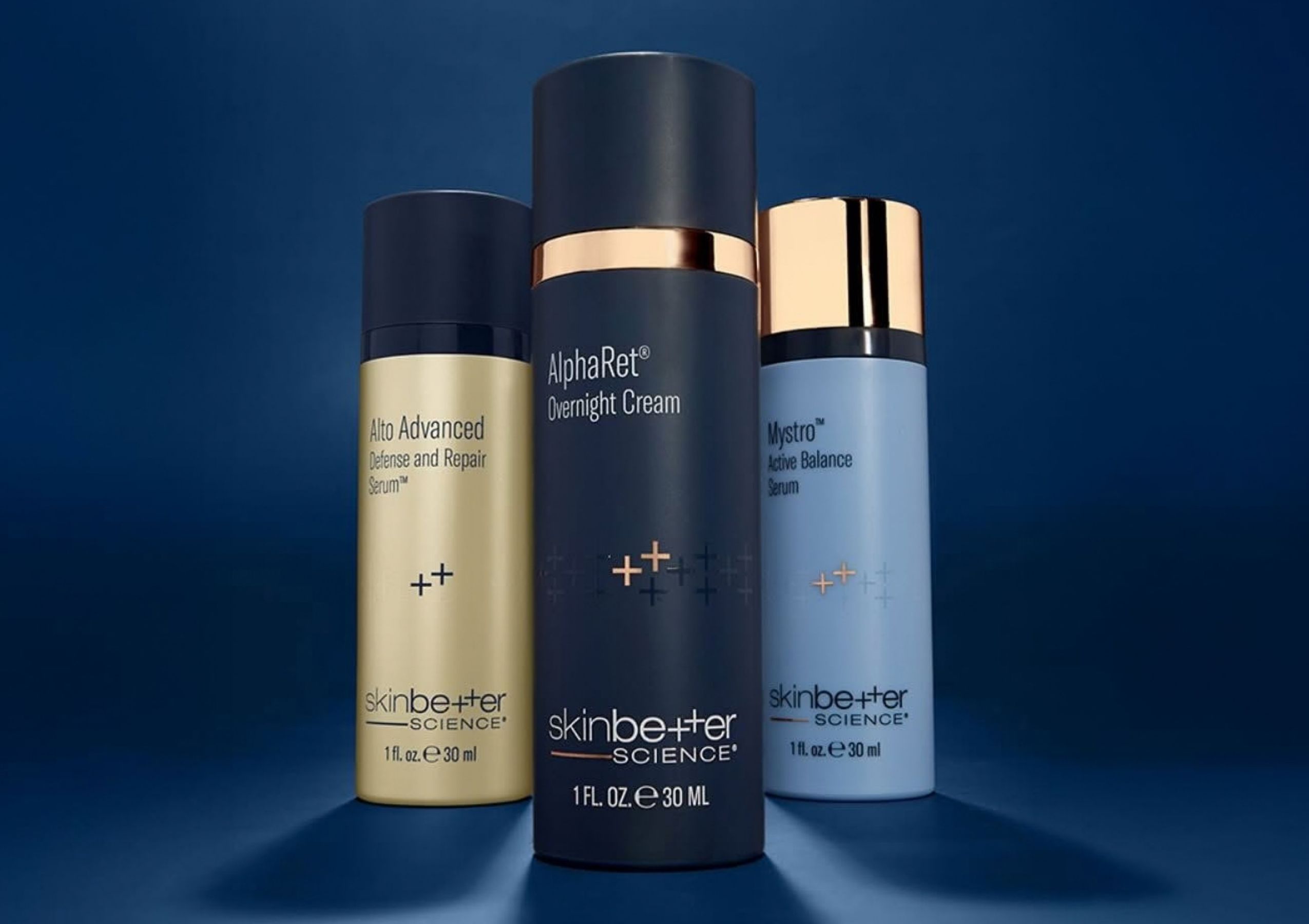 Three SkinCeuticals serum bottles with droppers in orange, clear, and purple glass against a gray background, viewed from the front-inside edge of a display shelf, close-up.